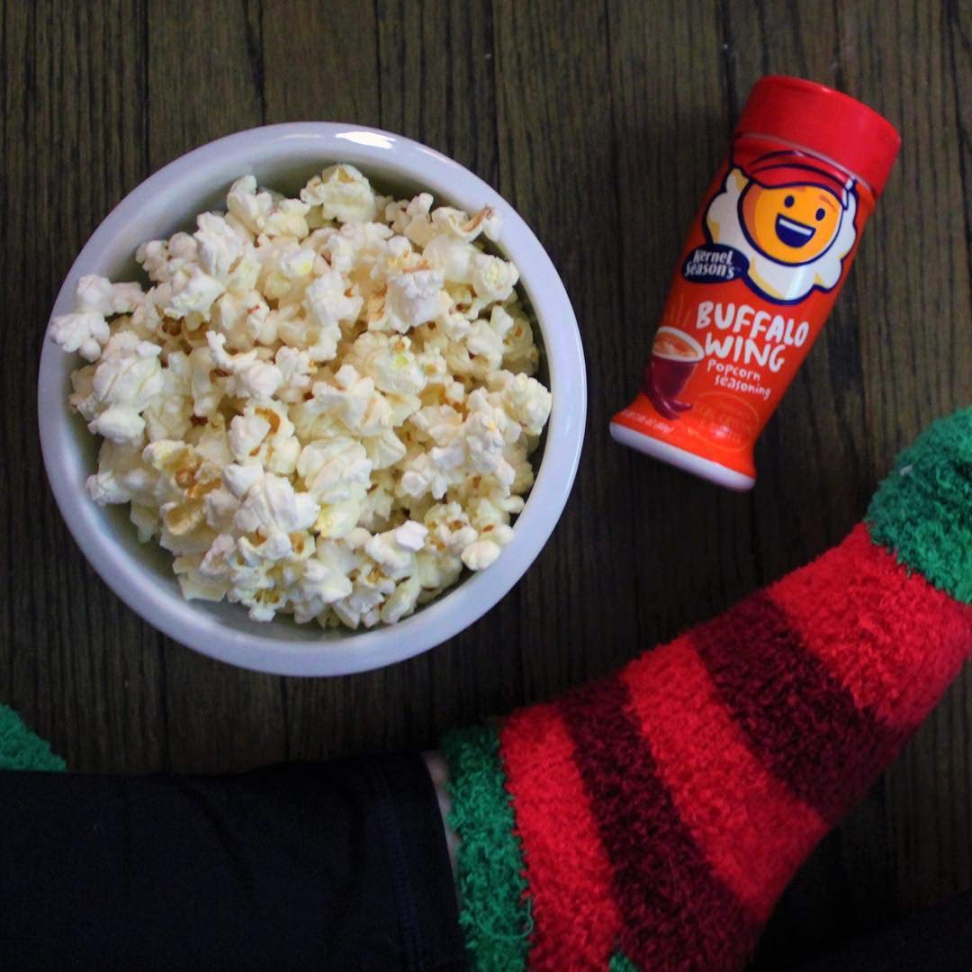 Pouring Kernel Season's Buffalo Wing on popcorn for spicy tang