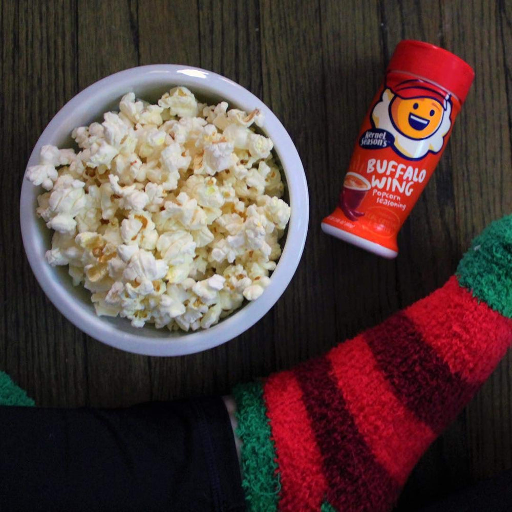 Pouring Kernel Season's Buffalo Wing on popcorn for spicy tang