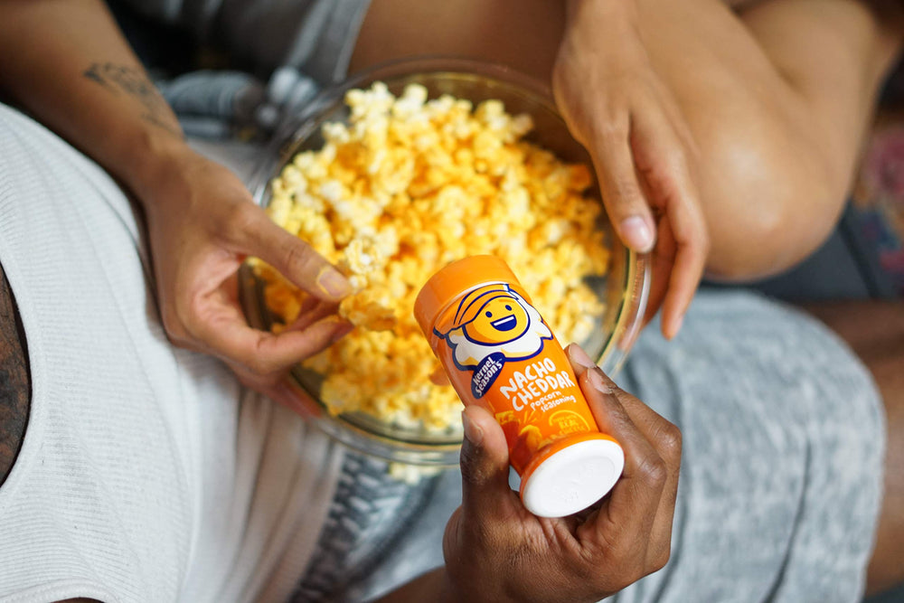 Kernel Season's Nacho Cheddar shaker dusting popcorn for quick flavor boost.