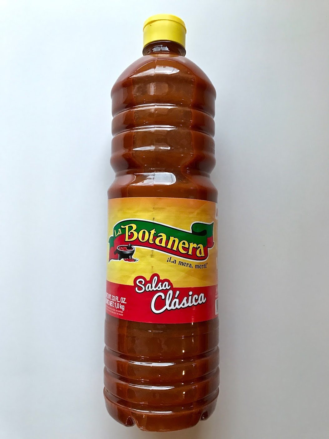 La Botanera Clasica hot sauce bottle, red, adds bold flavor to grilled meats and tacos.