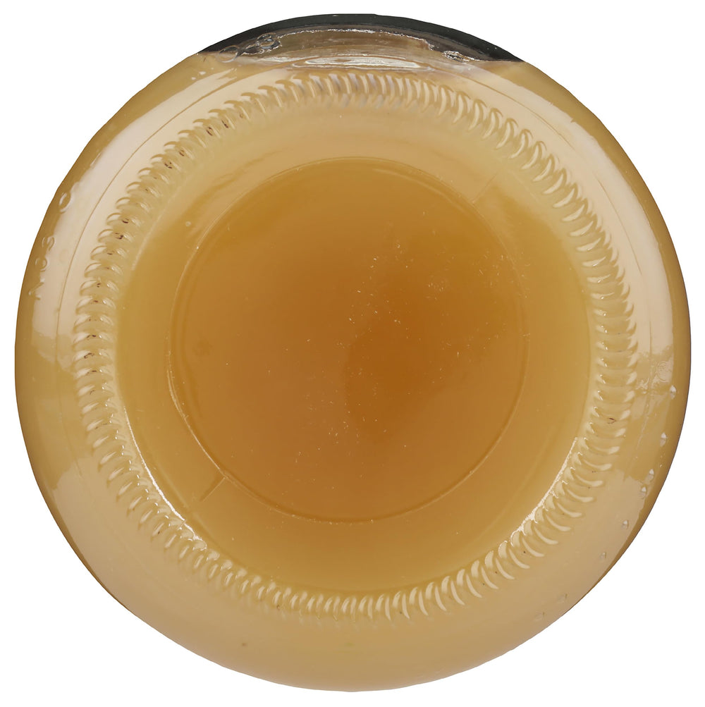 Lakewood Apple Juice being poured into a glass with fresh apples nearby.