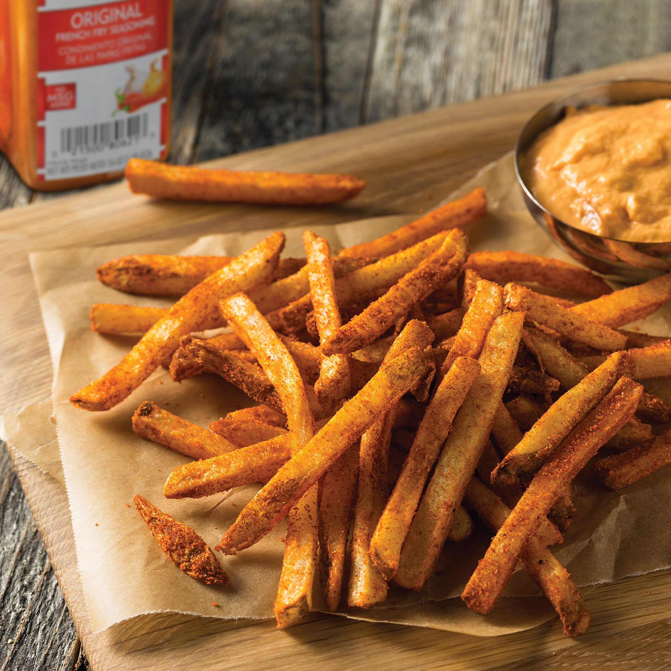 Pouring Lawry's Original French Fry Seasoning onto fries during prep.