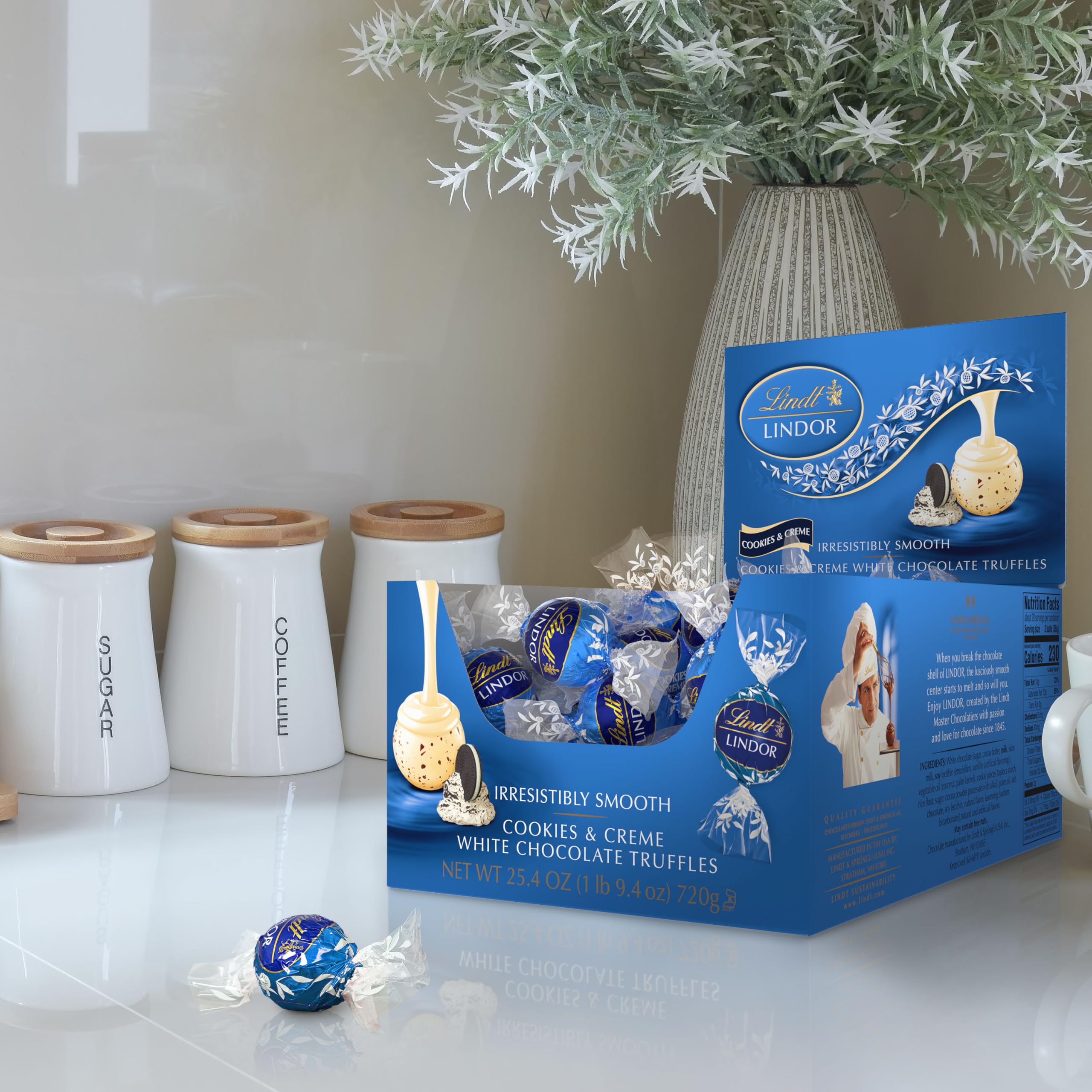Lindt LINDOR Cookies and Creme truffle close-up shows white shell with cookie bits.