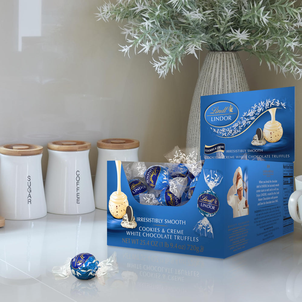 Lindt LINDOR Cookies and Creme truffle close-up shows white shell with cookie bits.