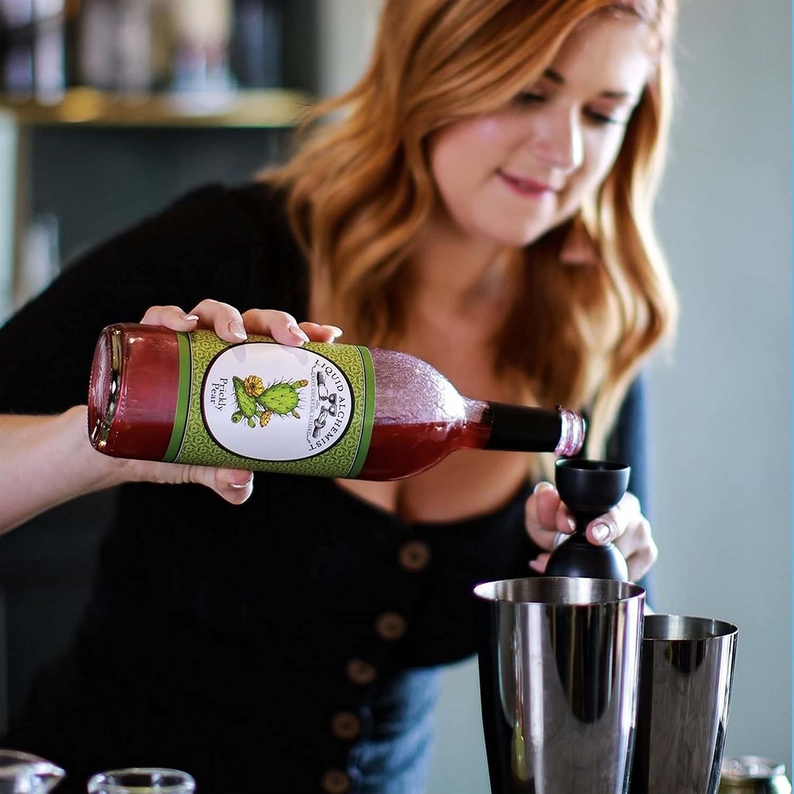 Prickly pear syrup beside fresh limes and club soda for mixed drinks.