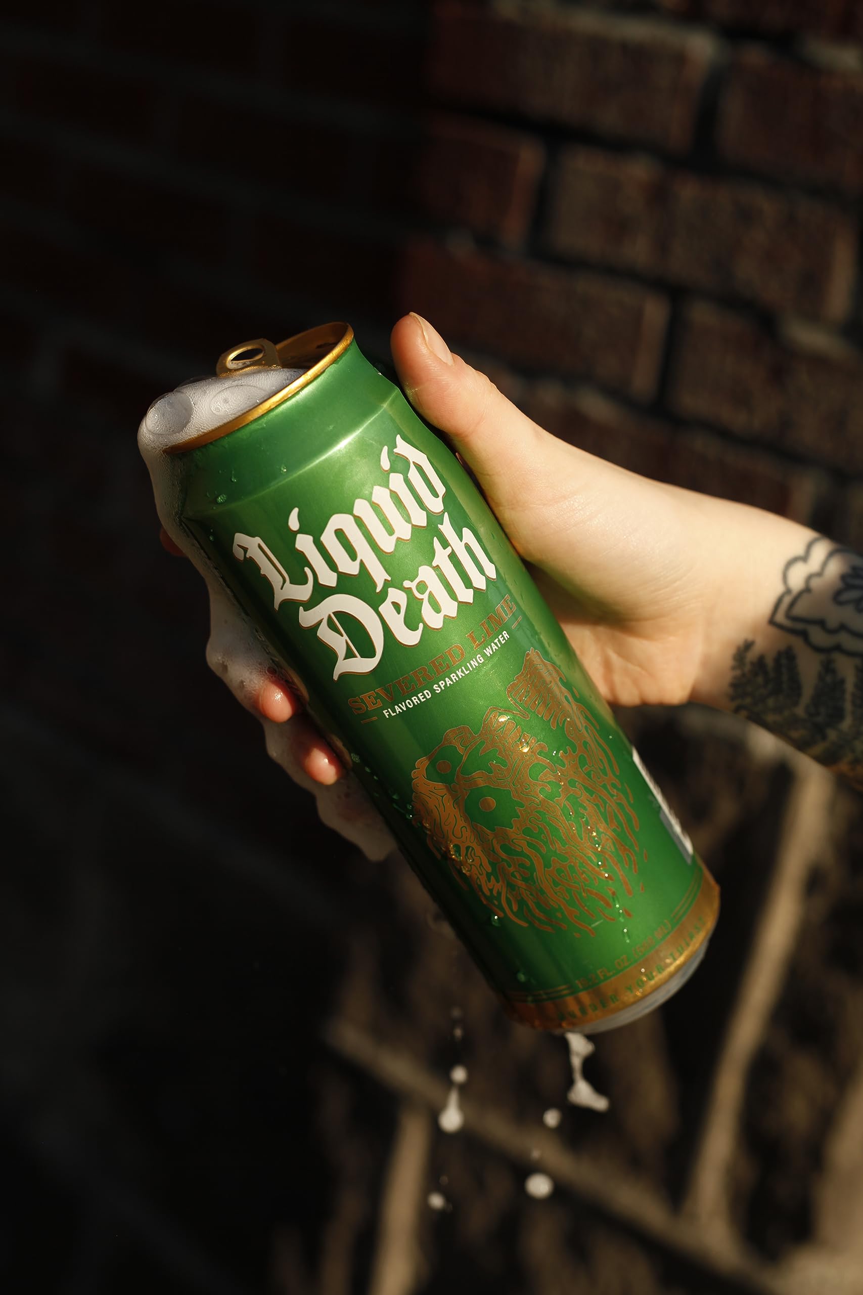 Liquid Death Severed Lime aluminum cans beside recycling bin promoting reduced plastic waste