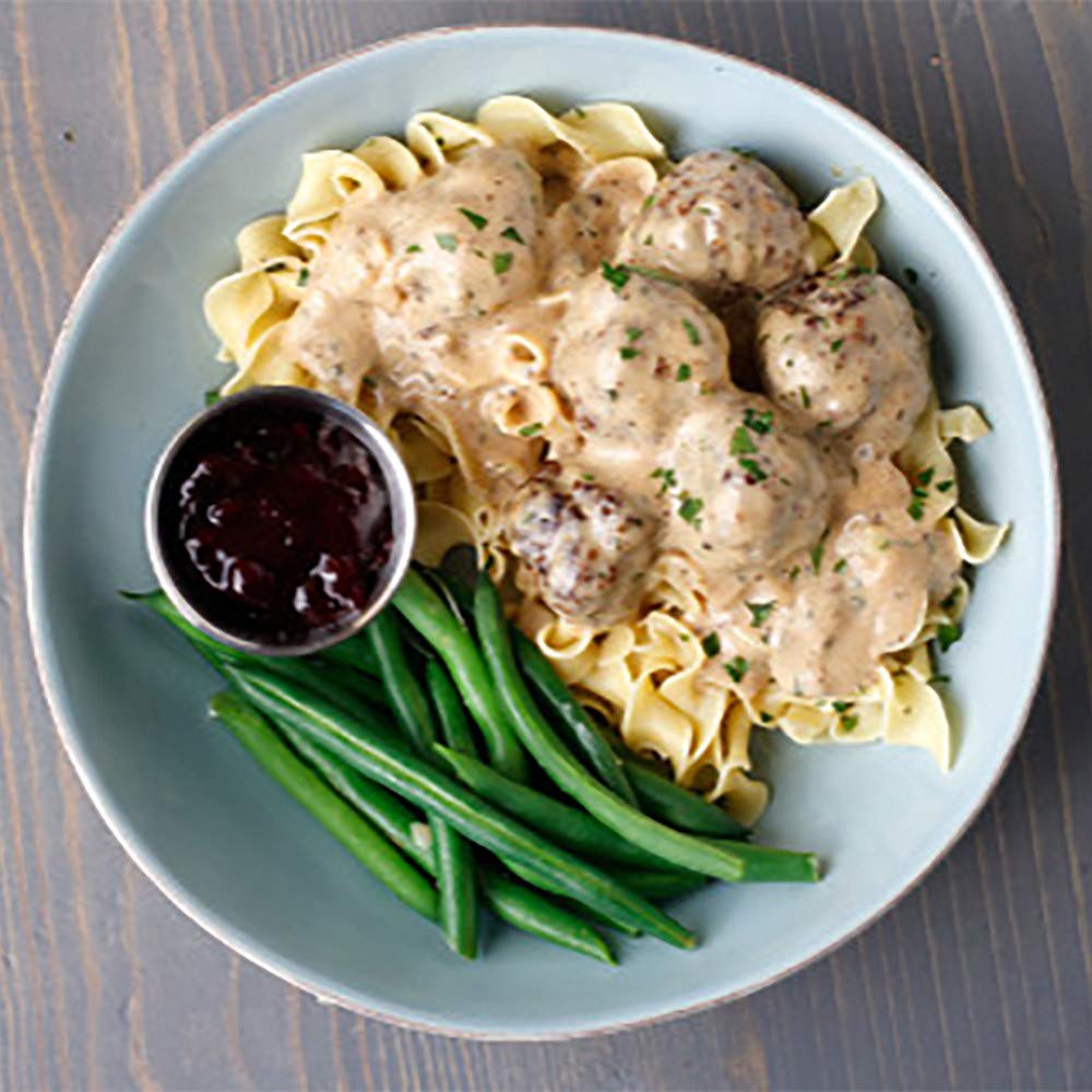 Creamy sauce being poured over noodles with McCormick seasoning.