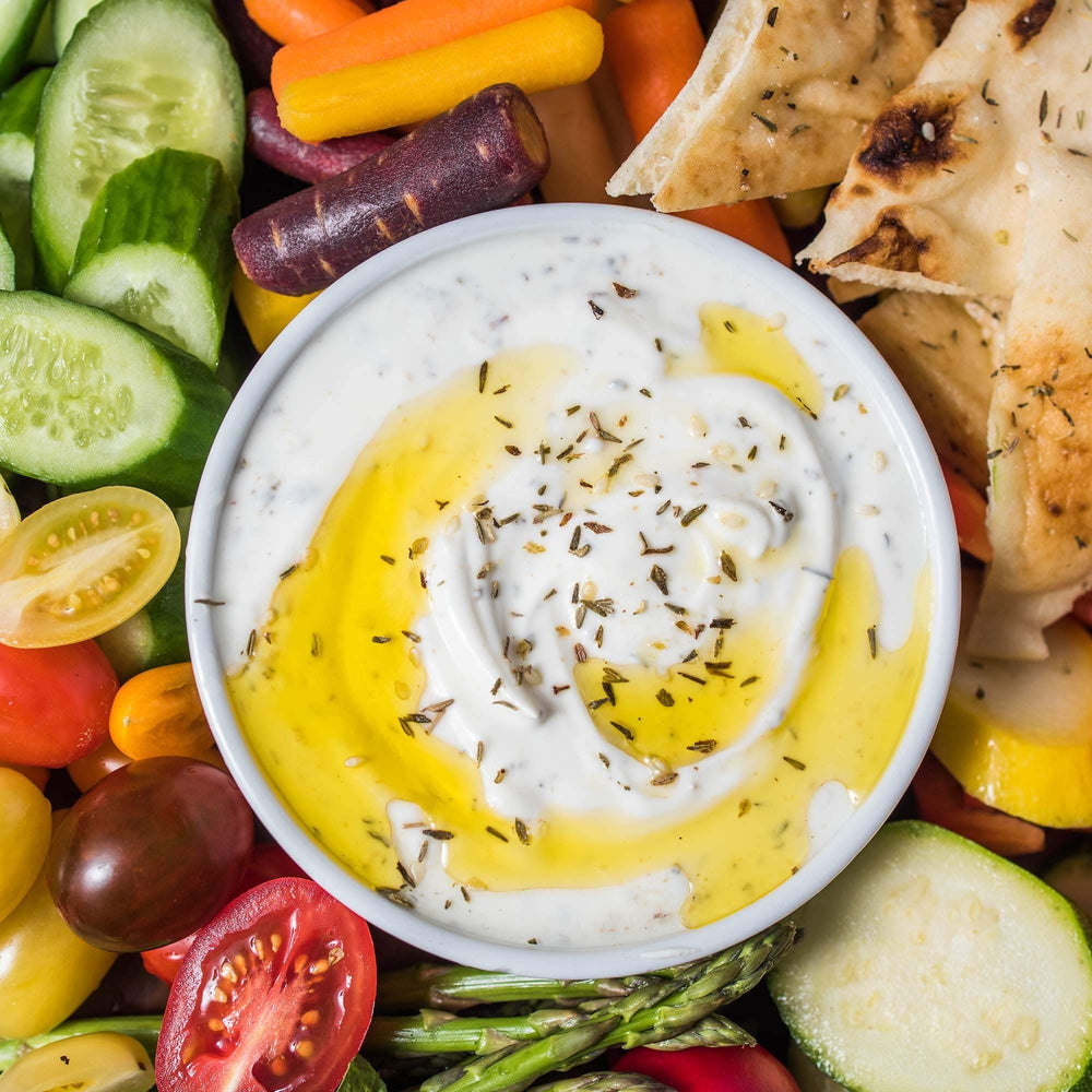 Sprinkling Za'atar over hummus with McCormick Culinary for Mediterranean flair.