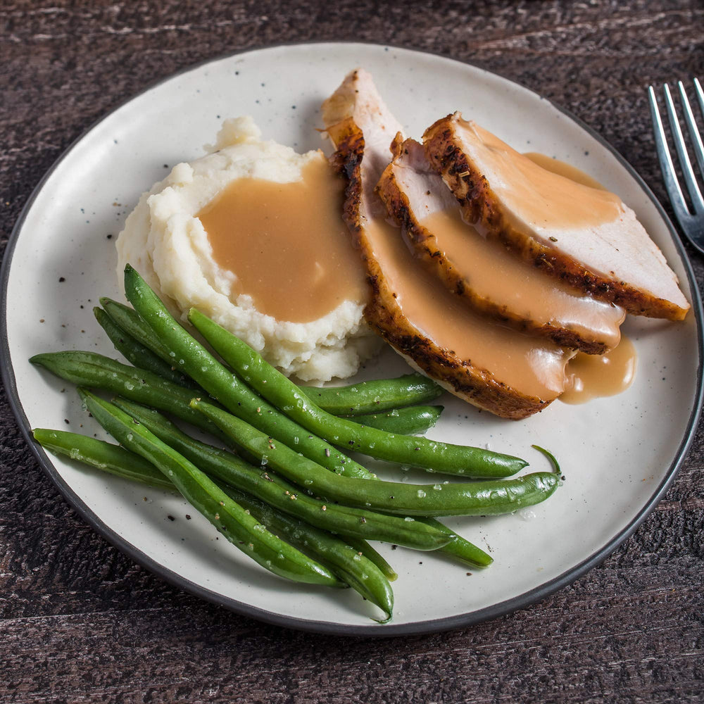 Pouring McCormick turkey gravy mix into a pan for a rich sauce.