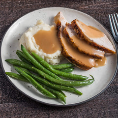 Pouring McCormick turkey gravy mix into a pan for a rich sauce.