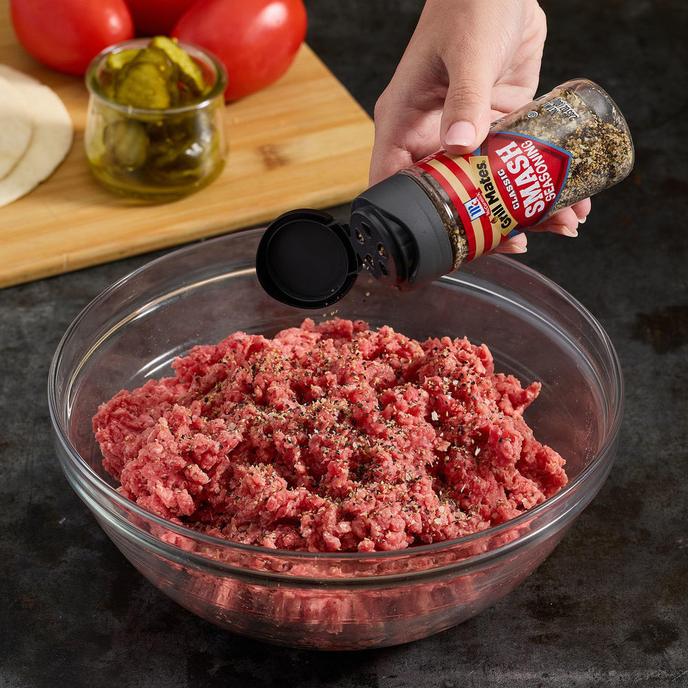 Burger assembly with melted cheese and McCormick Grill Mates Classic Smash Seasoning.