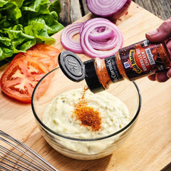 Sprinkling McCormick Grill Mates Nashville Hot Chicken Seasoning on chicken before grilling