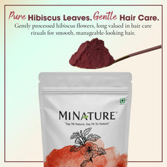 Minature hibiscus powder scoop beside jar for easy portioning