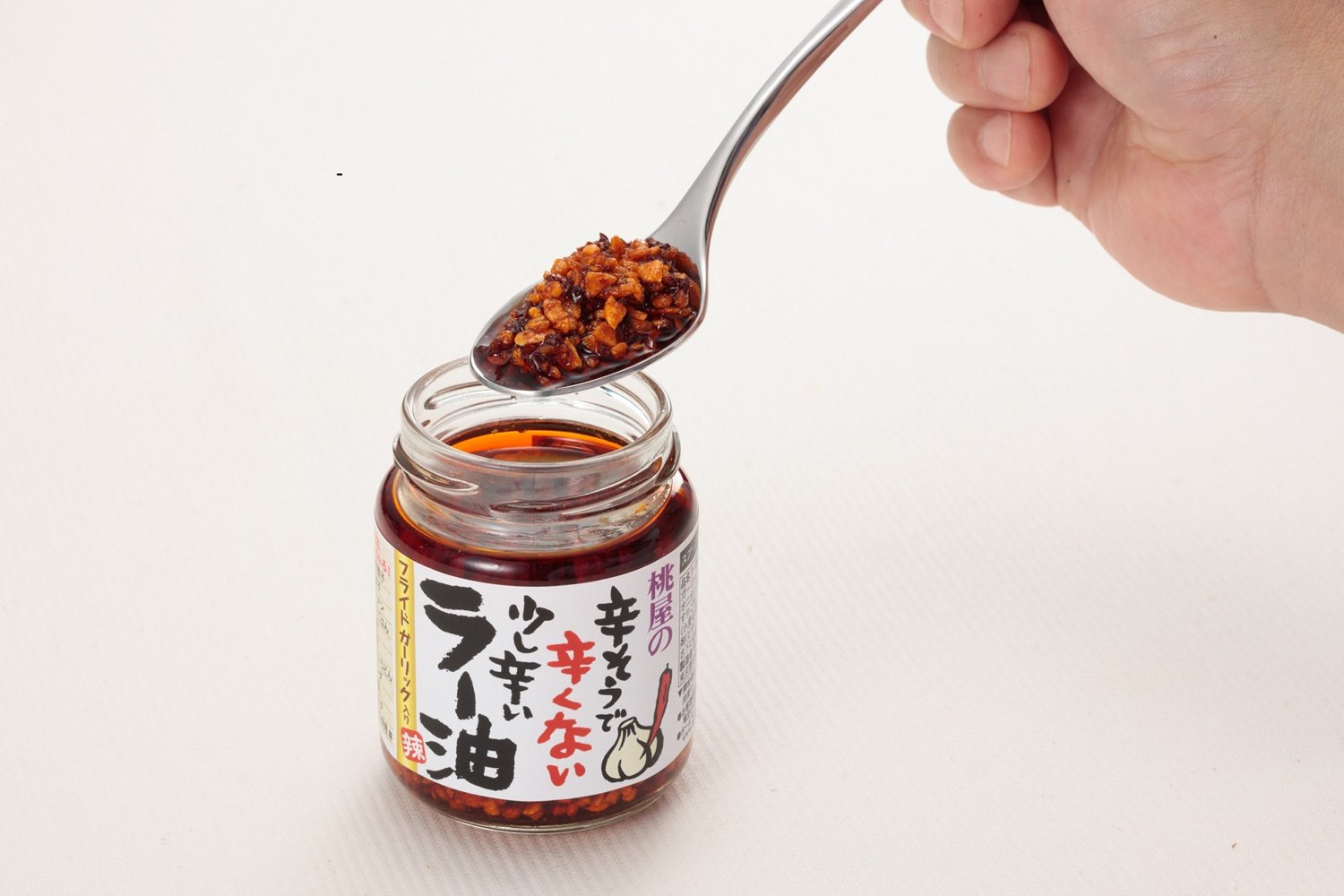 Momoya chili oil close-up shows garlic and chili peppers.