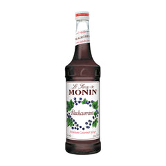 Monin Blackcurrant Syrup bottle on a bar enhances beverages.
