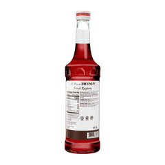 Monin Raspberry Syrup pour streams into a glass, great for espresso drinks and mocktails.