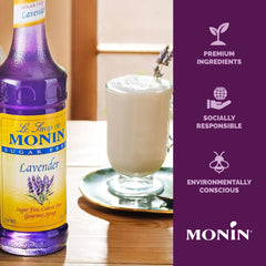 Monin Lavender Syrup bottle beside a refreshing cocktail.