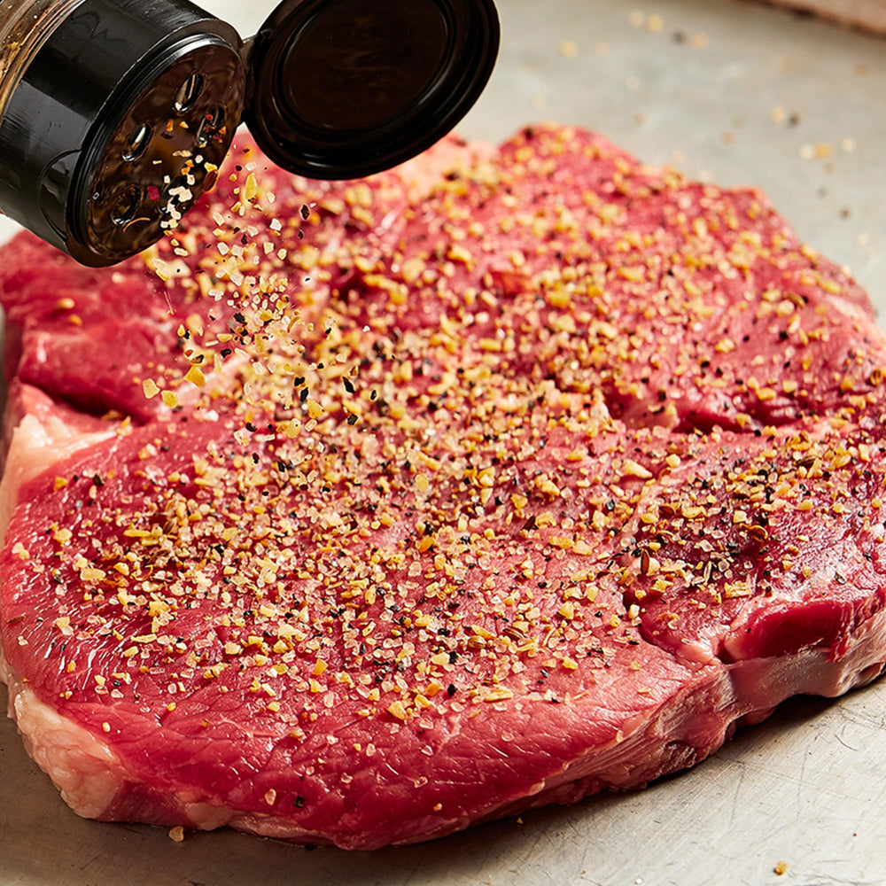 Montreal seasoning shaker ready to sprinkle on meat.