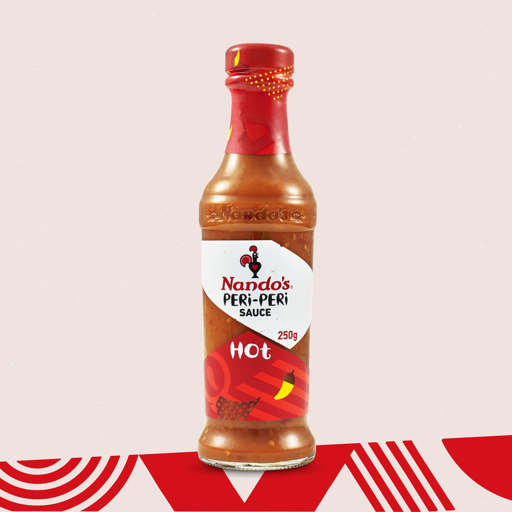 Nando's Hot Peri-Peri sauce bottle on table with tacos emphasizes versatile flavor.