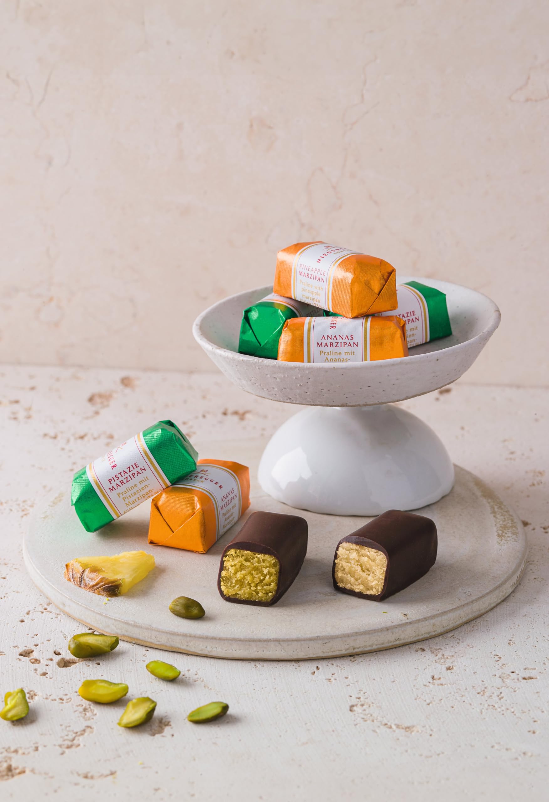 Niederegger pineapple-orange-pistachio-espresso marzipan coated in chocolate, vibrant flavor options.