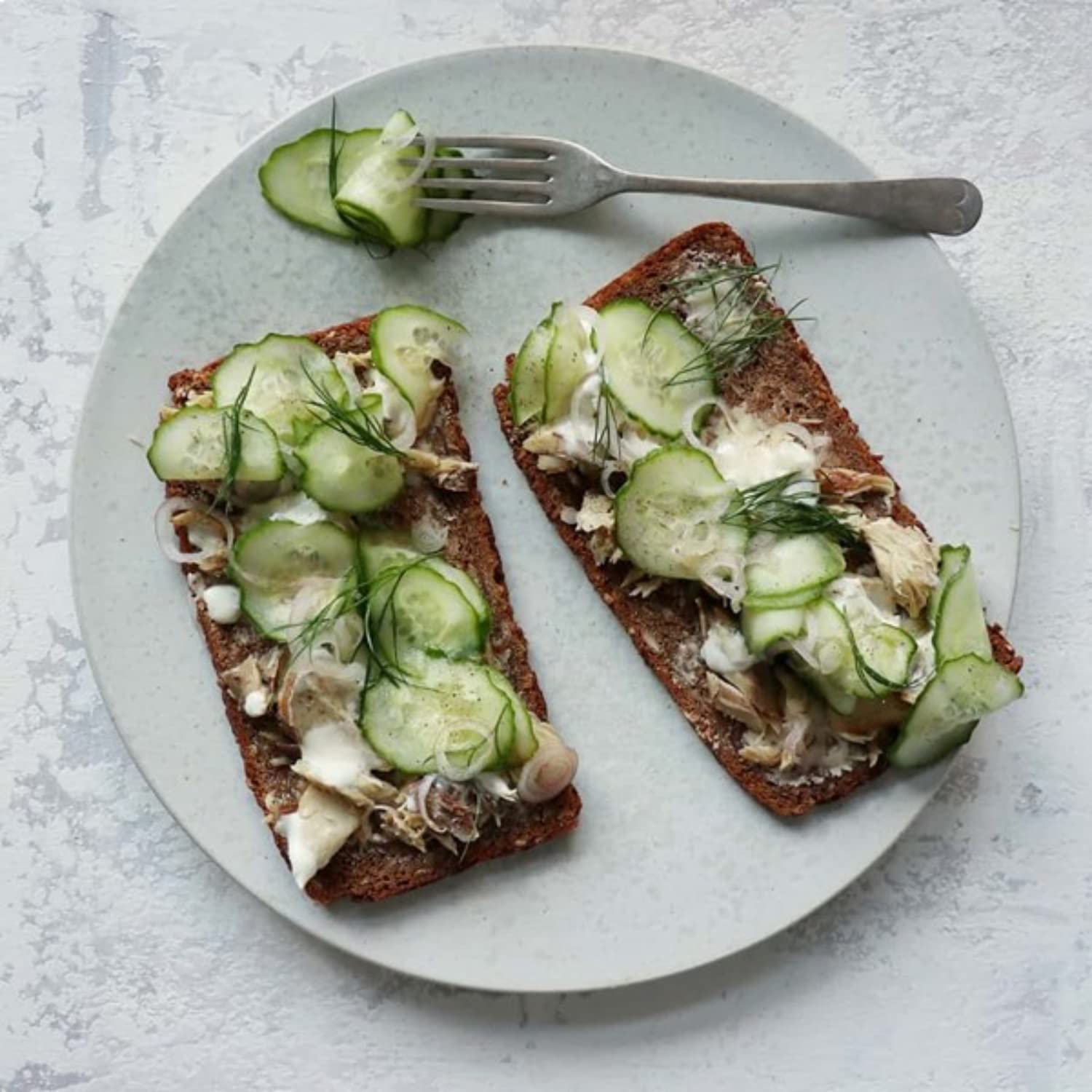 Opened Nuri Mackerel Spiced in Olive Oil can with cucumber and chili reveals flavoring.