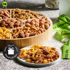 Nut Cravings reusable round wooden tray showcases the snack assortment for easy gifting