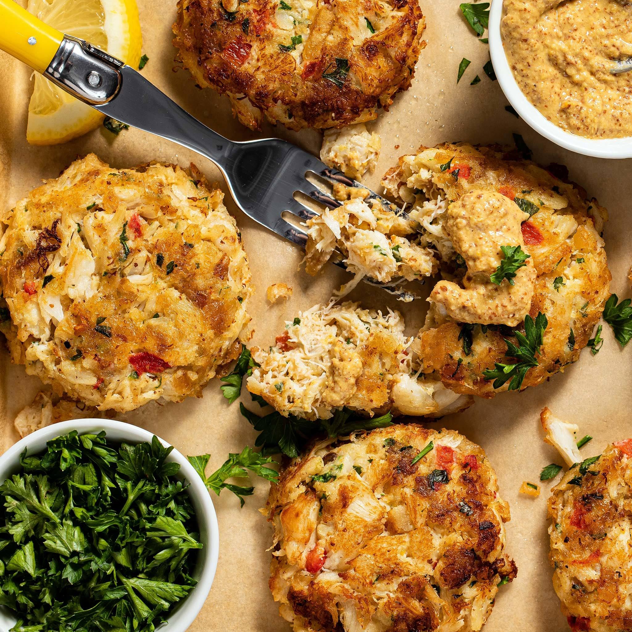Family dinner scene featuring OLD BAY crab cakes served with lemon and herbs.