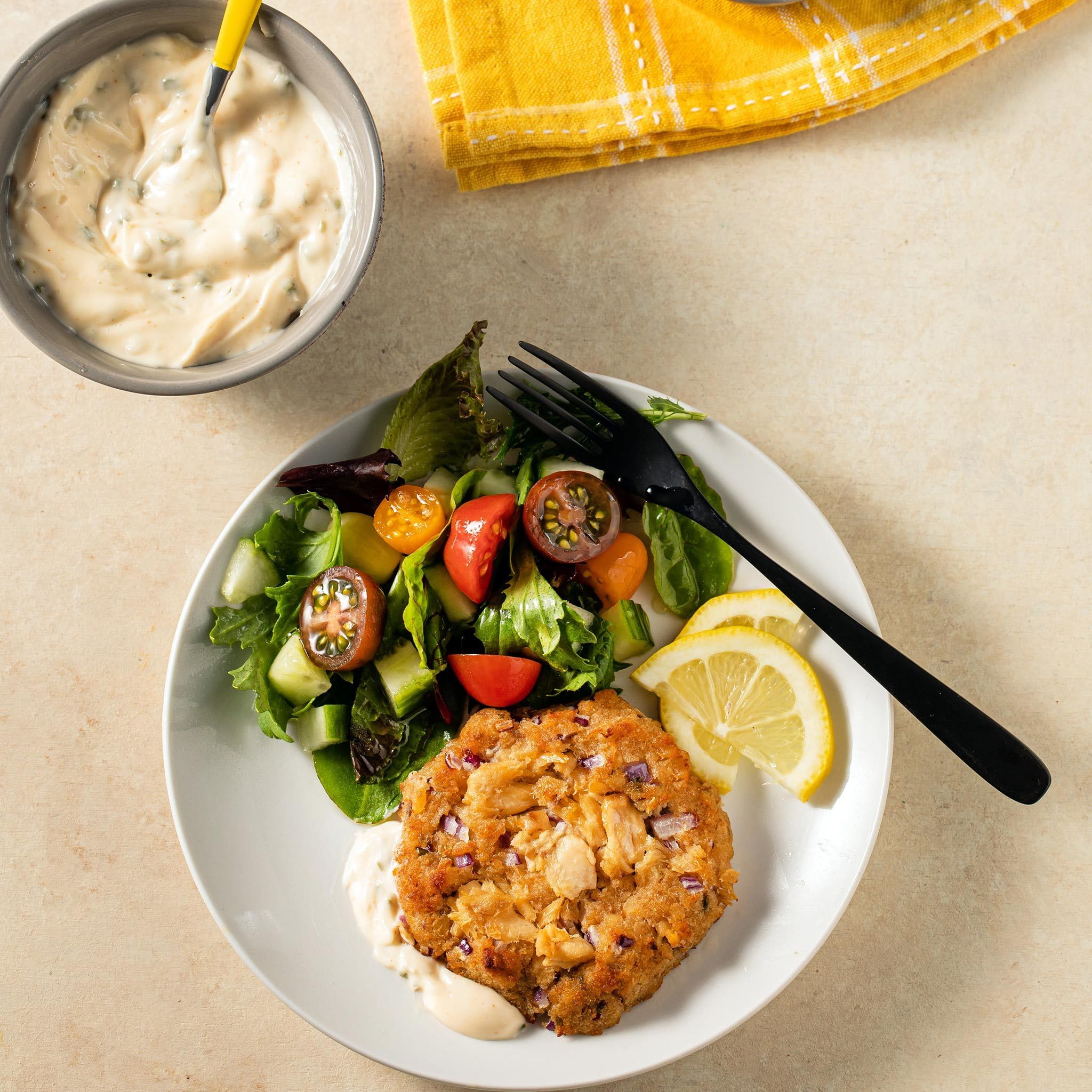 Old Bay salmon cakes plated with lemon wedges and herbs