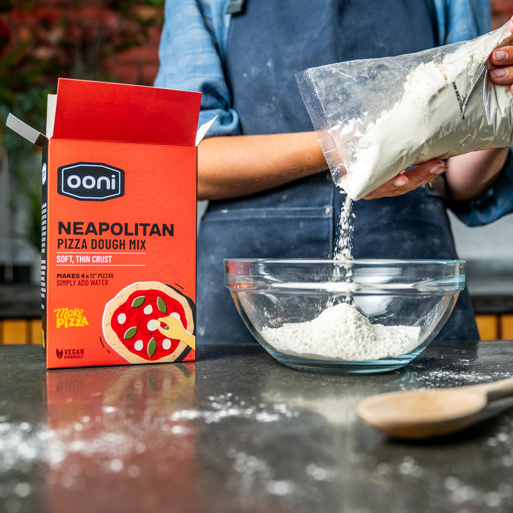 Ooni dough being stretched into round shapes for four pizzas.