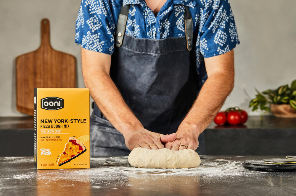 Ooni New York Style dough stretching, showcasing flexible dough ready for shaping.