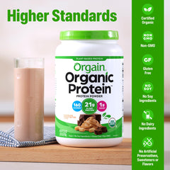 Pouring chocolate peanut butter shake with Orgain powder in a tall glass.