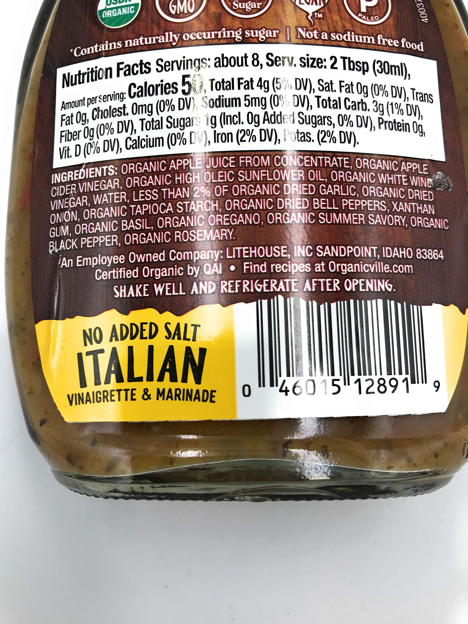 Pouring Organicville salt-free Italian dressing over a fresh salad.