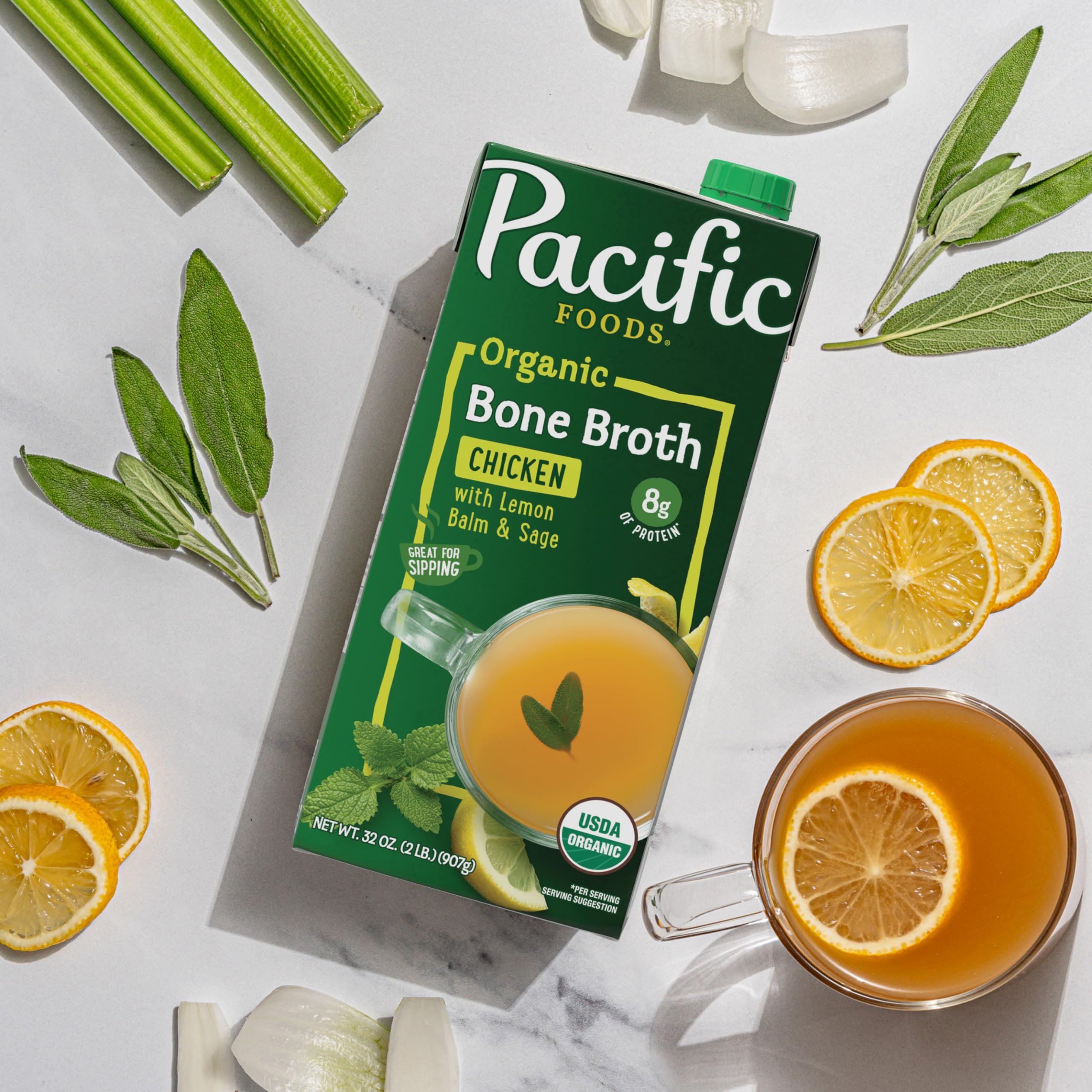 Pacific Foods organic broth with lemon balm and sage beside fresh lemon slices