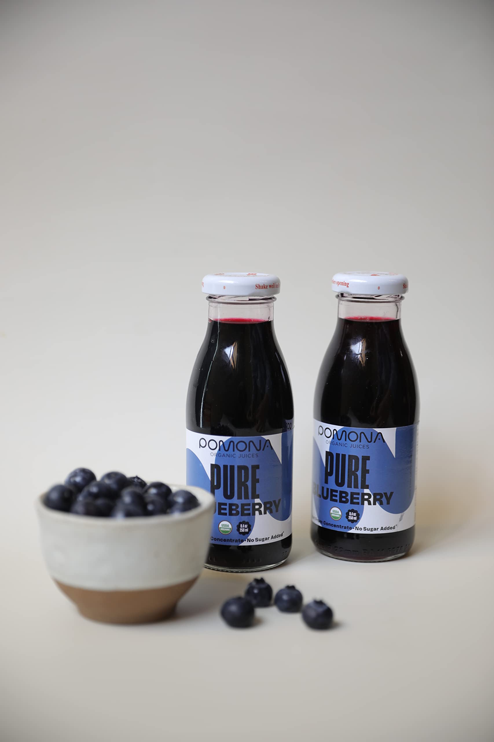 Pomona Blueberry Juice packaging highlighting glass bottle and sustainability.