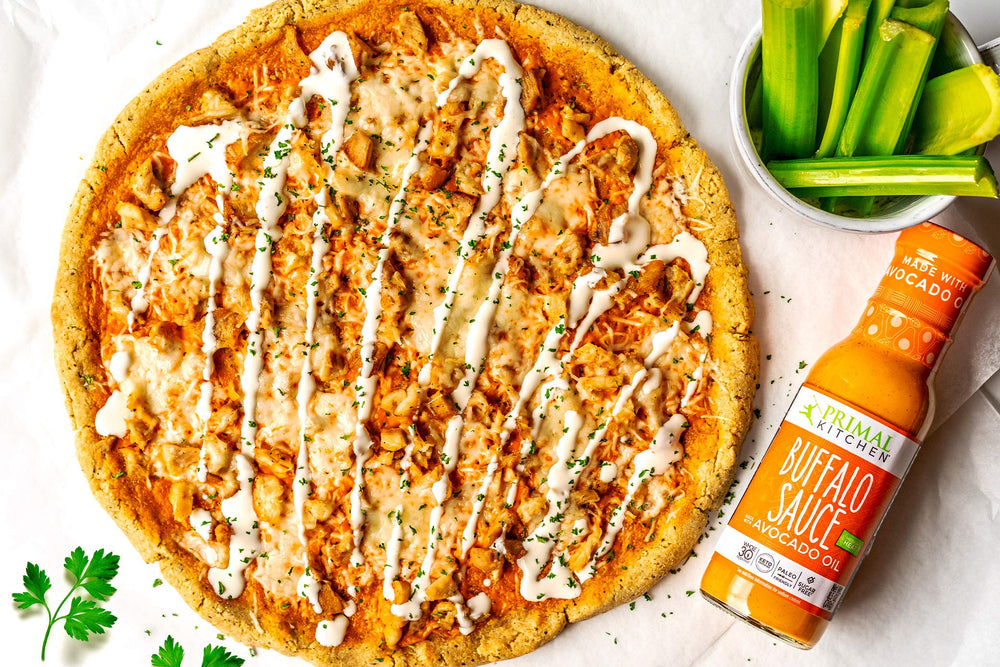 Primal Kitchen Buffalo Sauce wings-dipping scene, tangy medium heat.