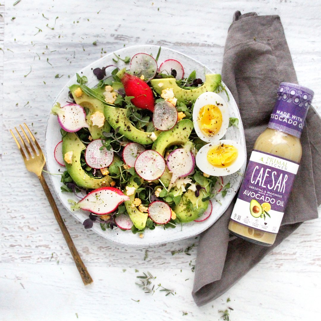 Primal Kitchen trio of dressings arranged for a fresh salad setup.