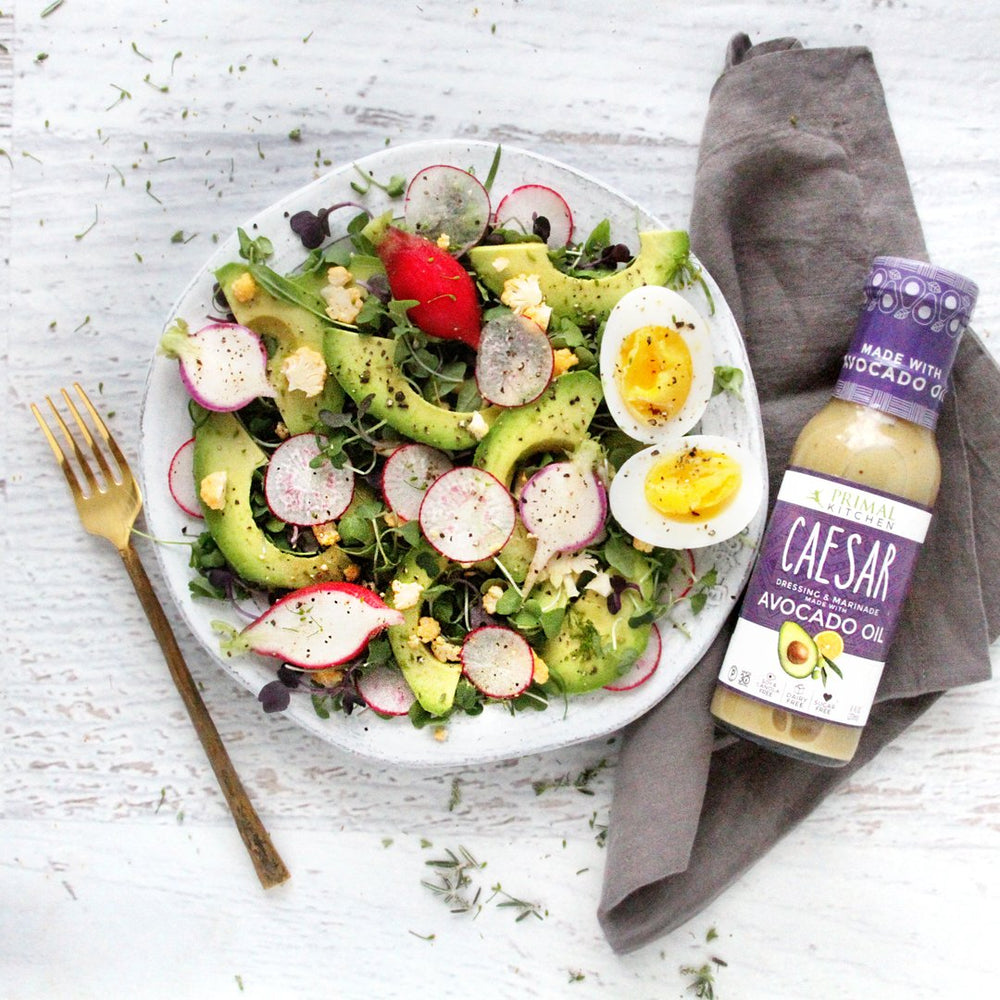 Primal Kitchen trio of dressings arranged for a fresh salad setup.