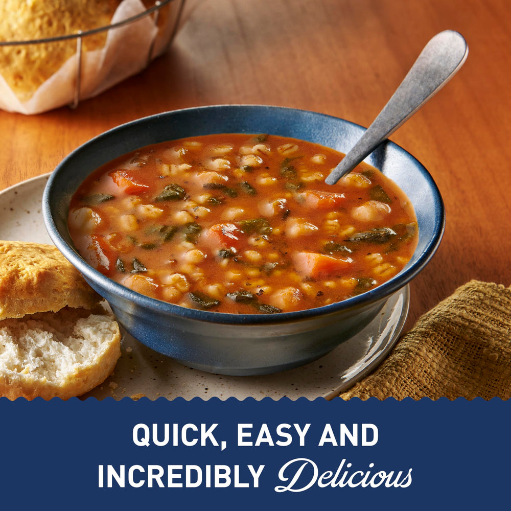 Pouring Progresso Protein Hearty Grain Vegetable Soup into a mug.
