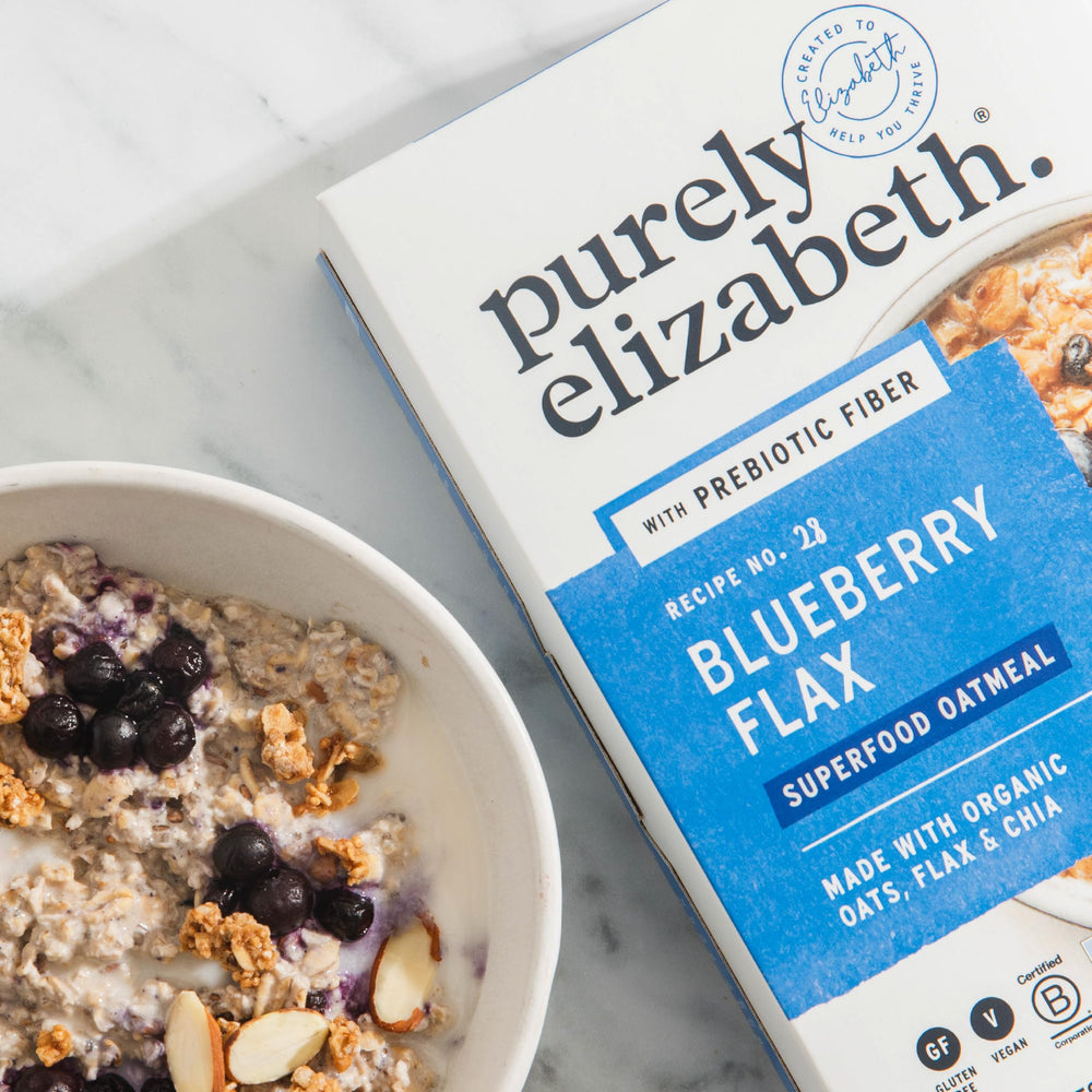 Spoon dipping into Purely Elizabeth Oatmeal showing creamy texture and mix of grains.