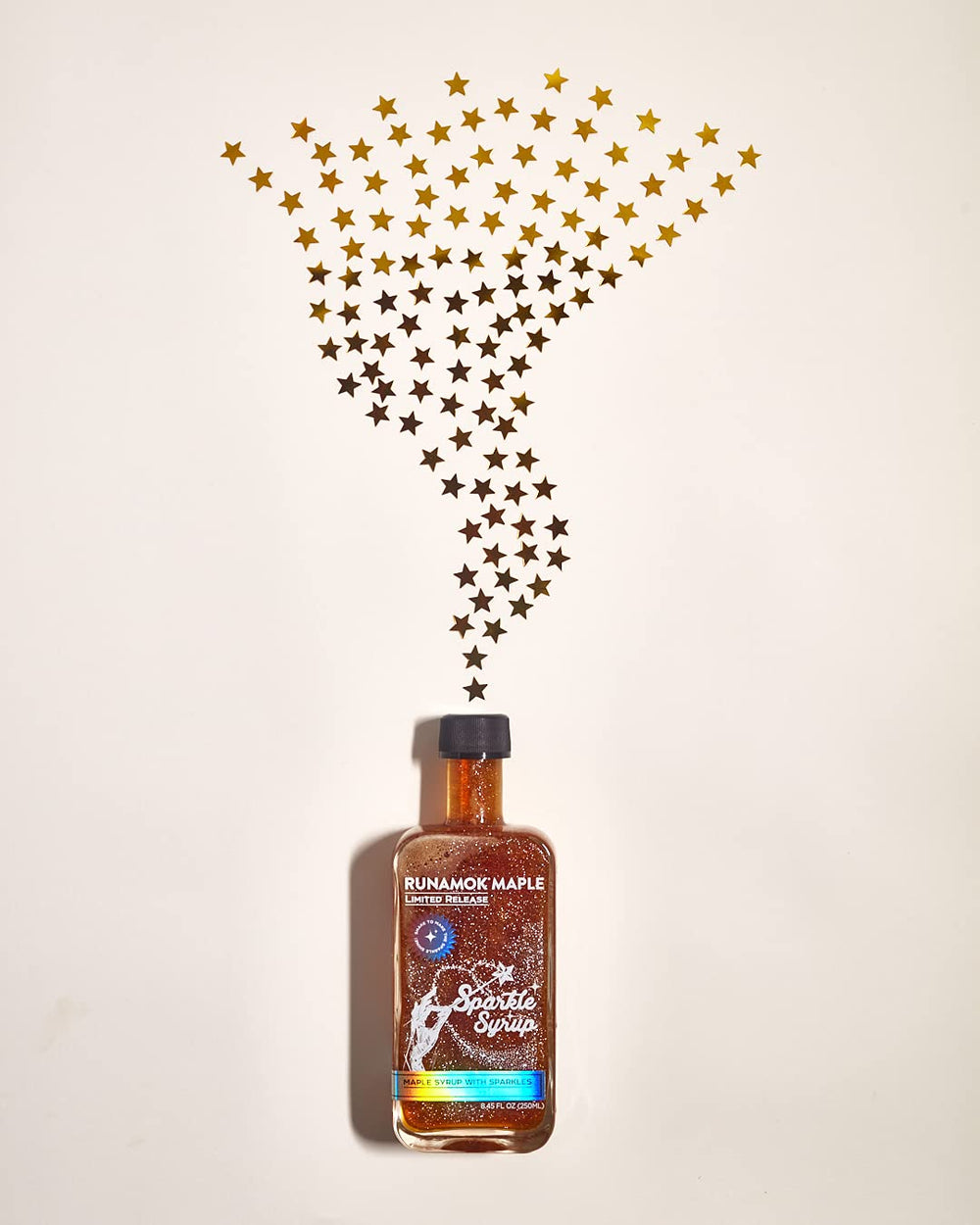 Spoon drizzling Runamok Sparkle Syrup on yogurt bowl for shimmering finish.