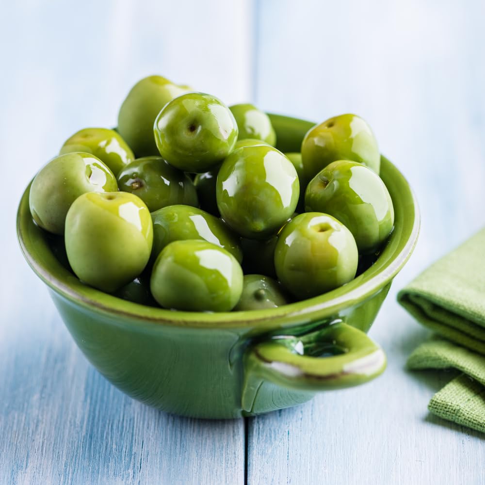Sanniti Castelvetrano olives on a platter with herbs and oil.