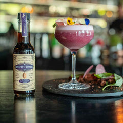 Pouring Scrappy's Lavender Bitters into a cocktail glass