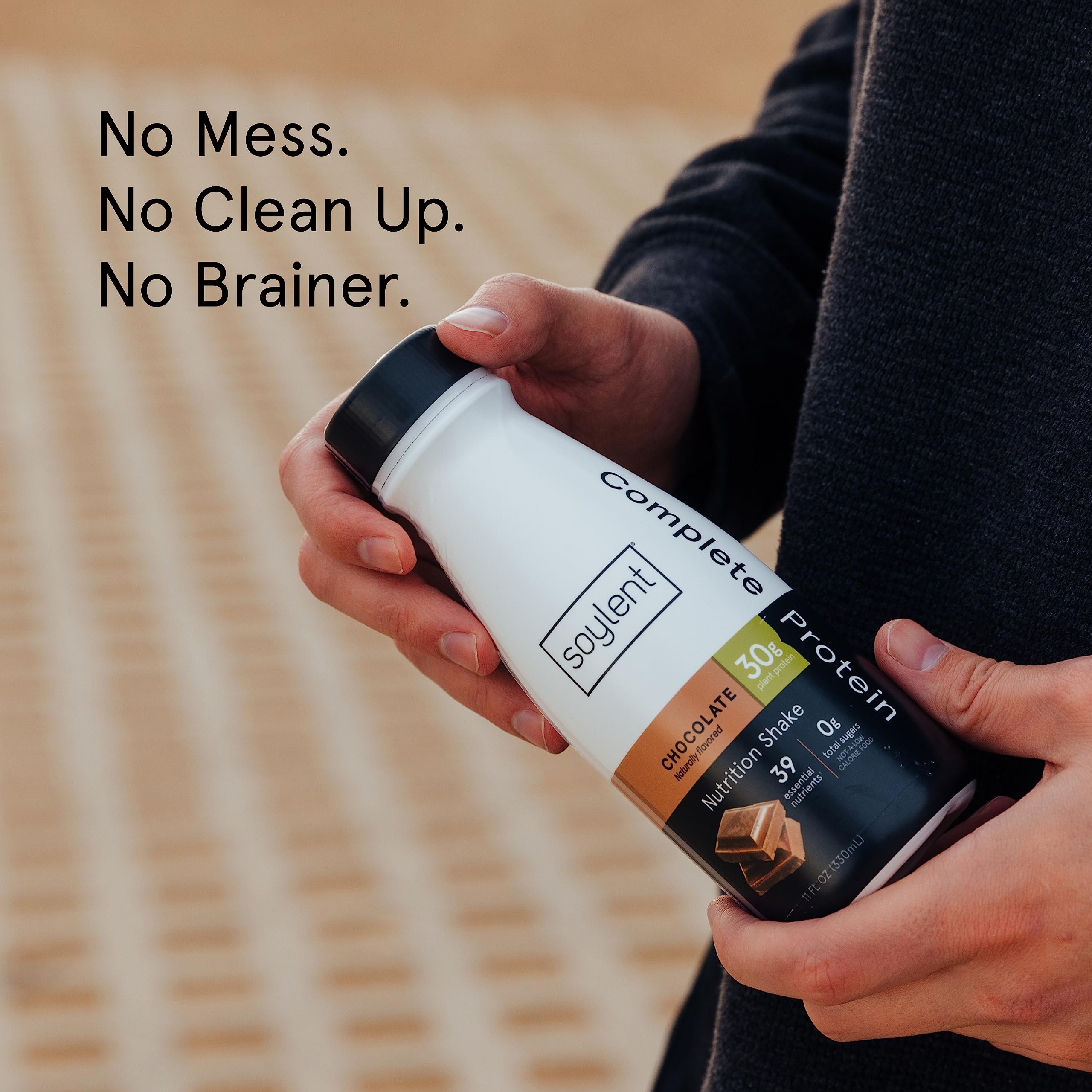 Soylent Complete Protein Shake Chocolate on desk with glass, ready-to-drink convenience.