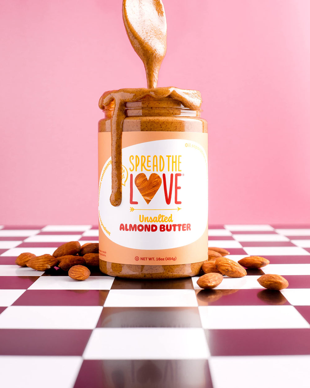 Spread The Love almond butter being stirred in a jar to show natural oil separation.