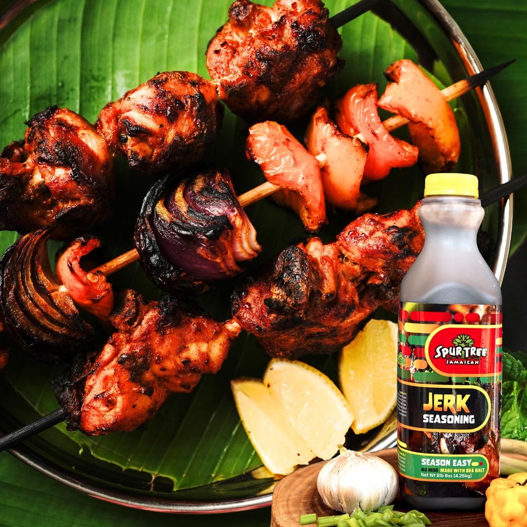 Spur Tree Jamaican Jerk Seasoning beside fresh scallions and peppers on kitchen counter.