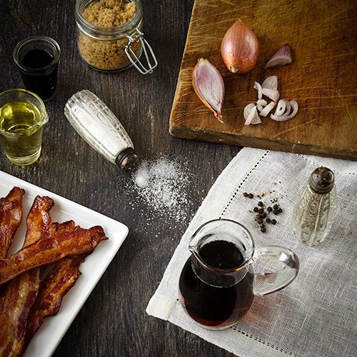 Stonewall Kitchen Maple Bacon Balsamic Dressing being poured over greens for a flavorful finish.
