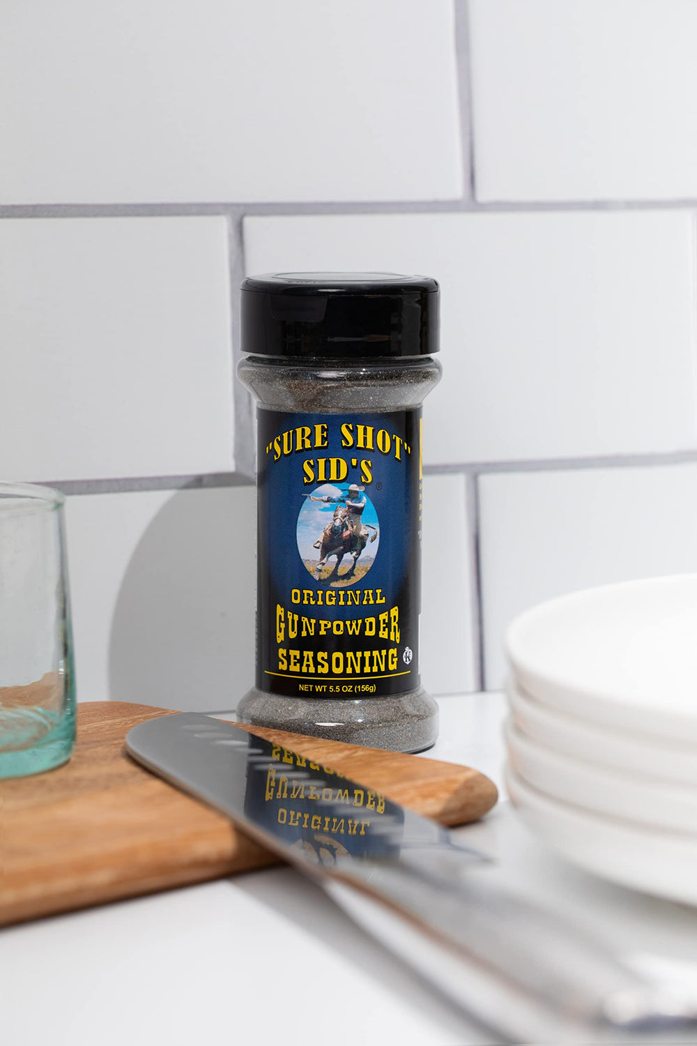 Sure Shot Sid's Gunpowder Seasoning jar beside sizzling grill.