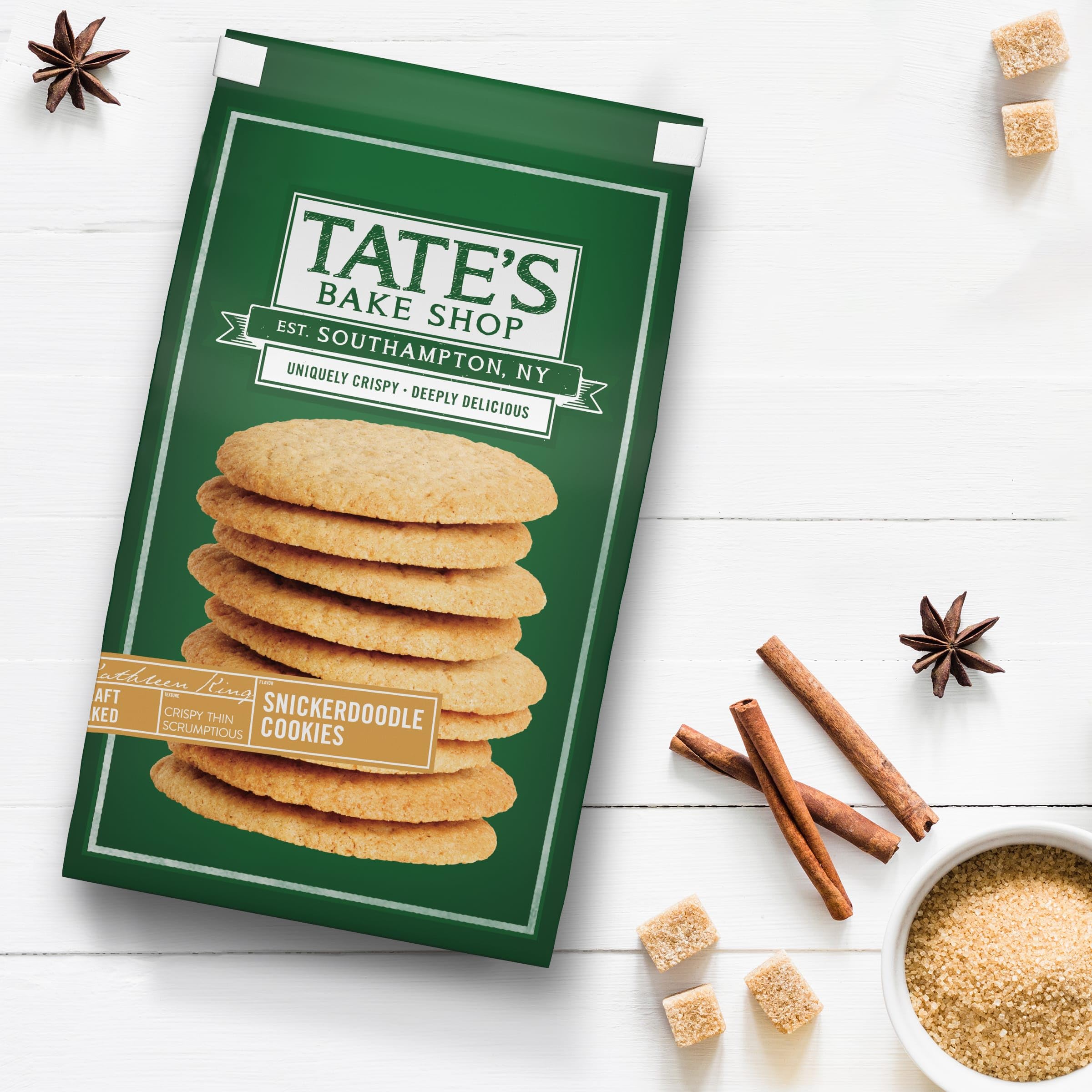 Tate's Snickerdoodle cookies beside a hot beverage in a cozy setting