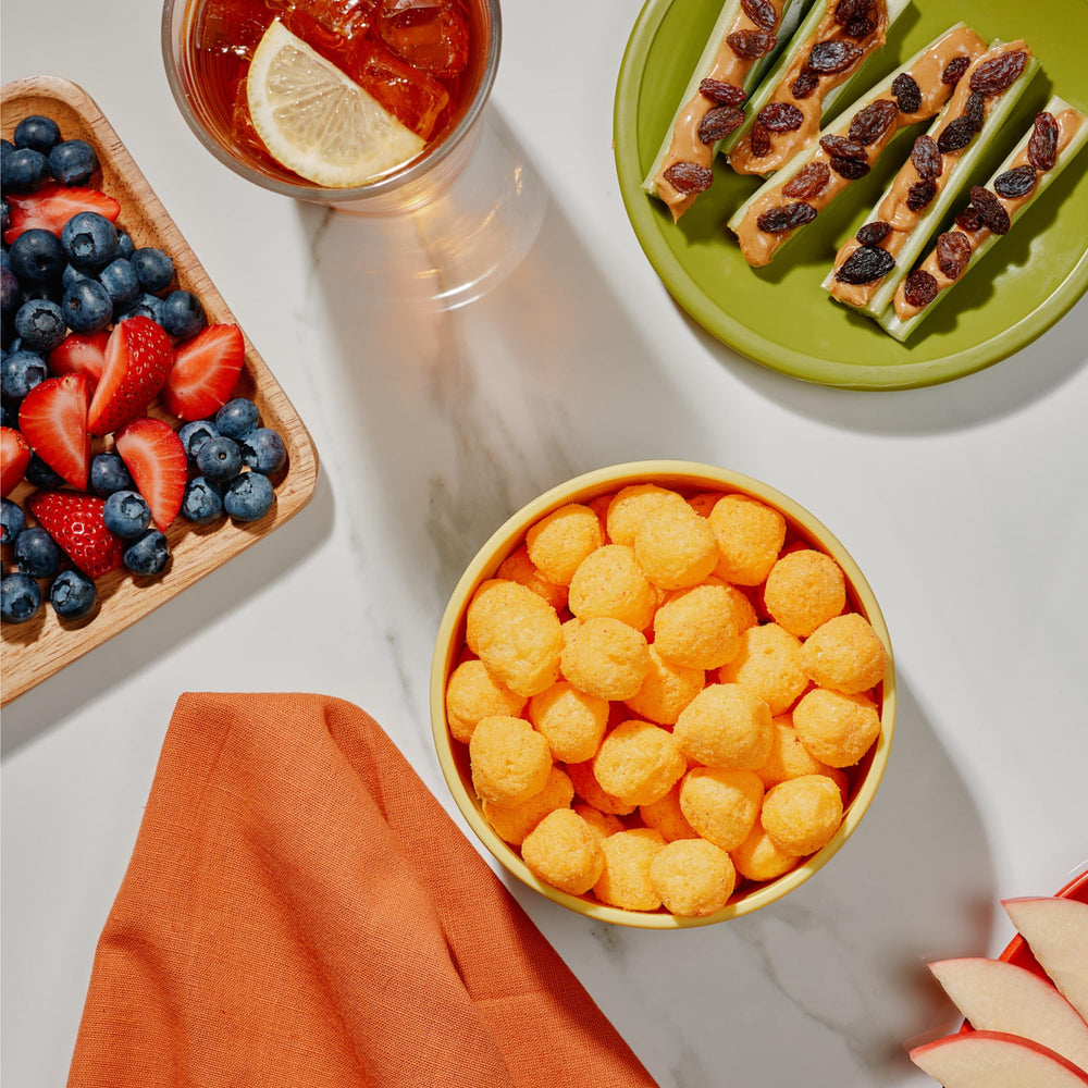 Kids enjoying The Good Crisp Company cheddar cheese balls as a lunchbox snack.