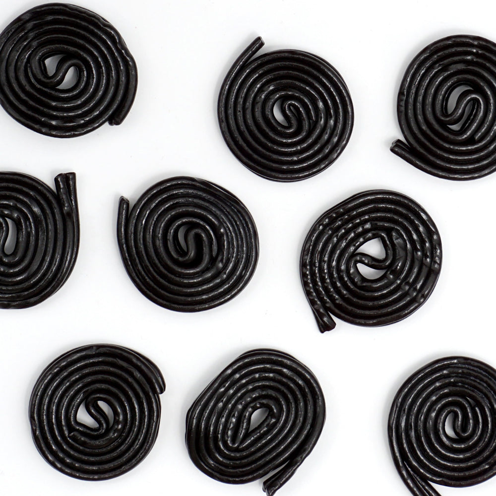 Licorice wheels beside coffee or tea for a satisfying afternoon treat.